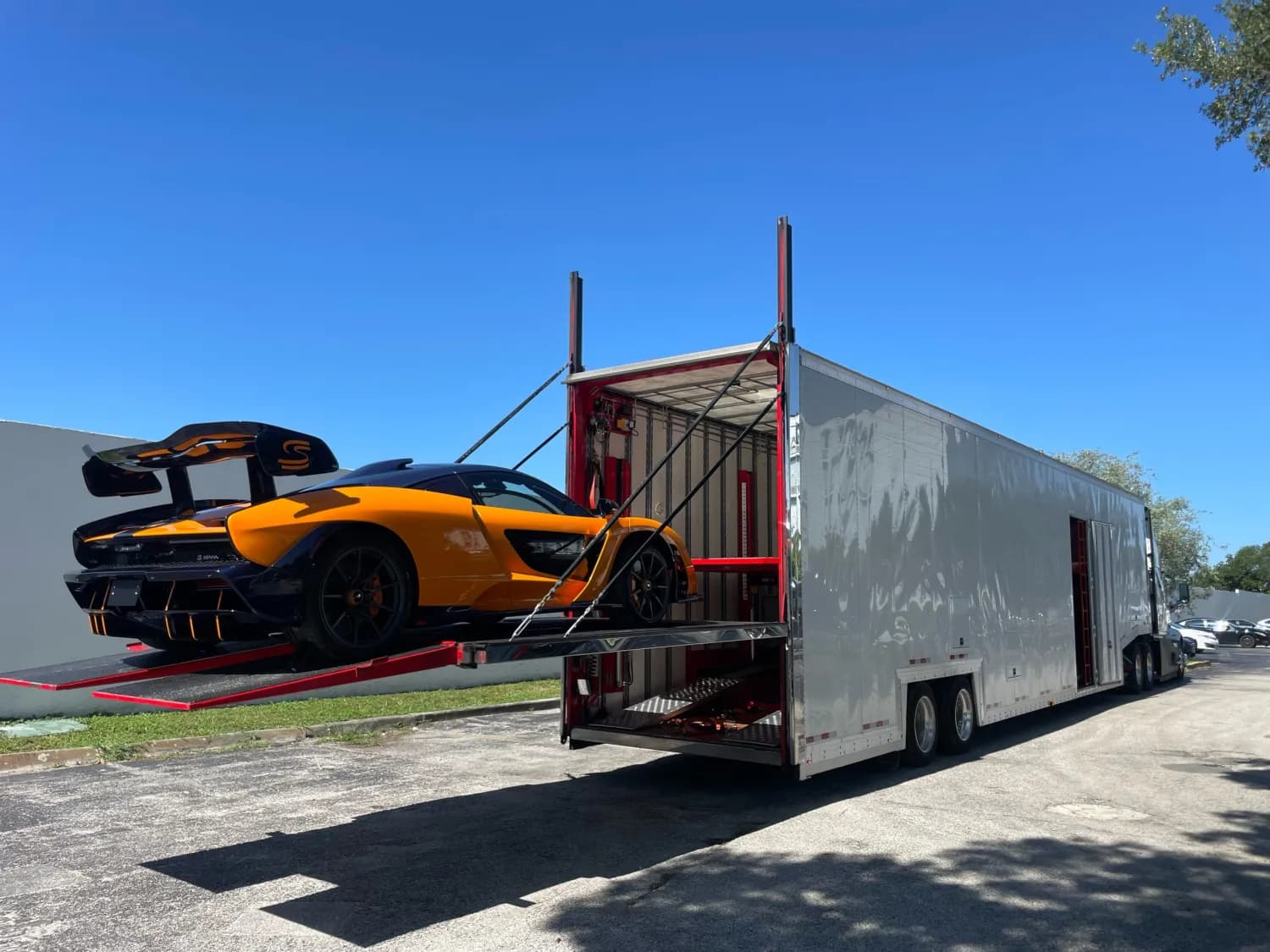 Orange sports car being loaded into an enclosed trailer