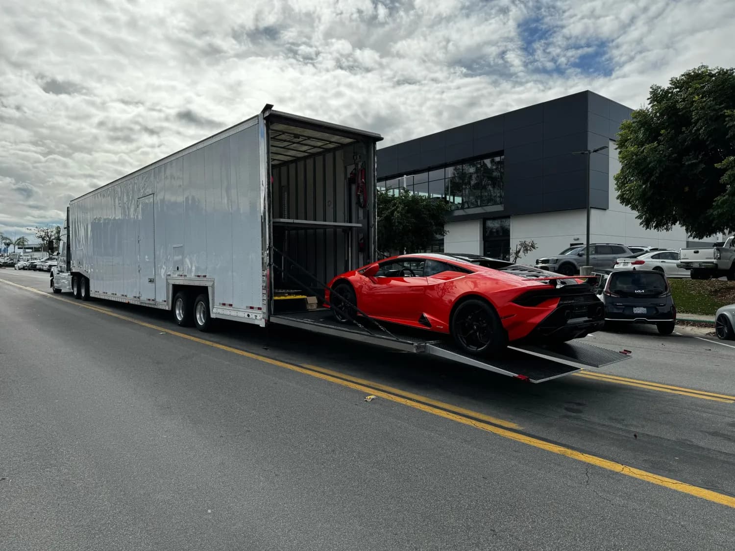 Red sports car beside an enclosed transport trailer